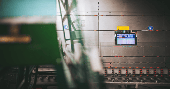 View of a glass factory with a wall screen displaying an ERP used for real-time production monitoring.