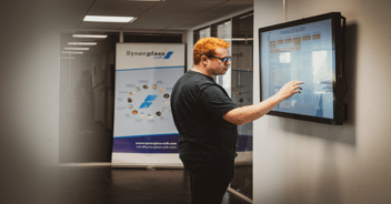 Dipendente che utilizza un touch screen interattivo situato all'ingresso dell'azienda per accedere alle informazioni.