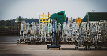 Flotte d'équipements de livraison de verre stationnés sur le parking d'une usine avec du verre dessus.