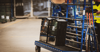 Glass transport racks loaded with small glass panels, lined up in an industrial space.