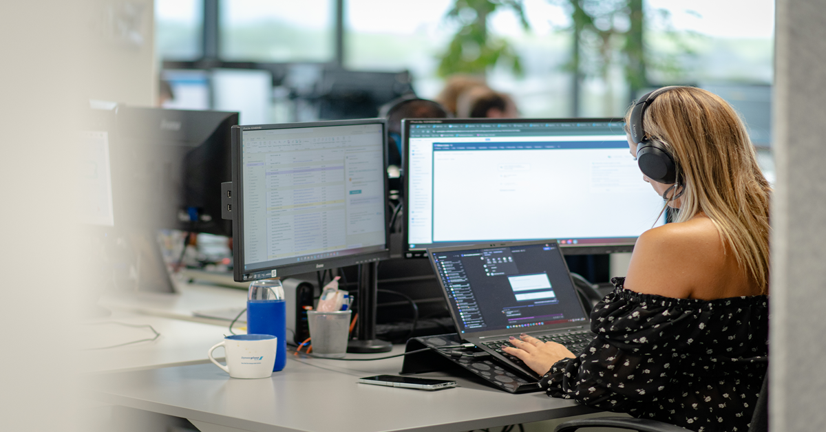 Impiegato che lavora su un computer dotato di due schermi, sullo schermo dei quali è visualizzato un ERP modulare.