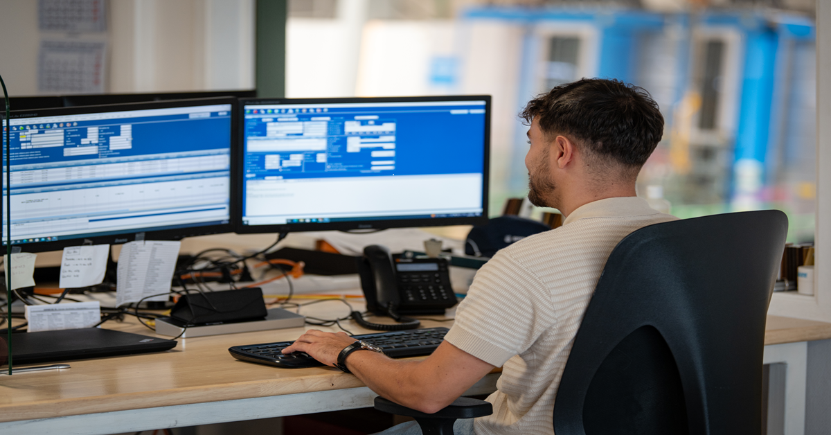 Impiegato che utilizza un ERP modulare sul suo computer nella sua postazione di lavoro, concentrato sulla gestione delle sue attività.